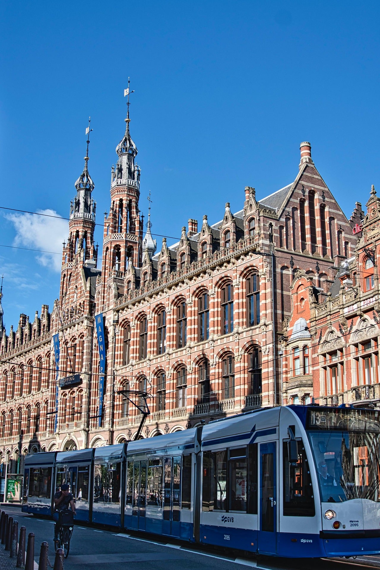 Amsterdam Centraal Station met passerende tram, perfect beeld voor levering van promotieartikelen, relatiegeschenken en bedrukte producten door heel Nederland, inclusief snelle service en lokale expertise.