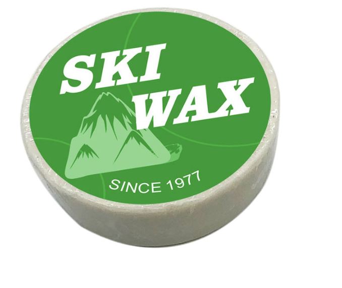 Green snowboard wax puck with a printed label