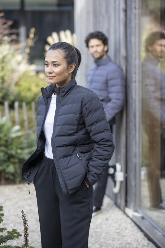 Model in gewatteerde jas, ideaal als bedrukte kleding voor promotioneel textiel, bedrijfskleding en relatiegeschenken in Nederland, geleverd met snelle EU-verzending en volledige personalisatie.