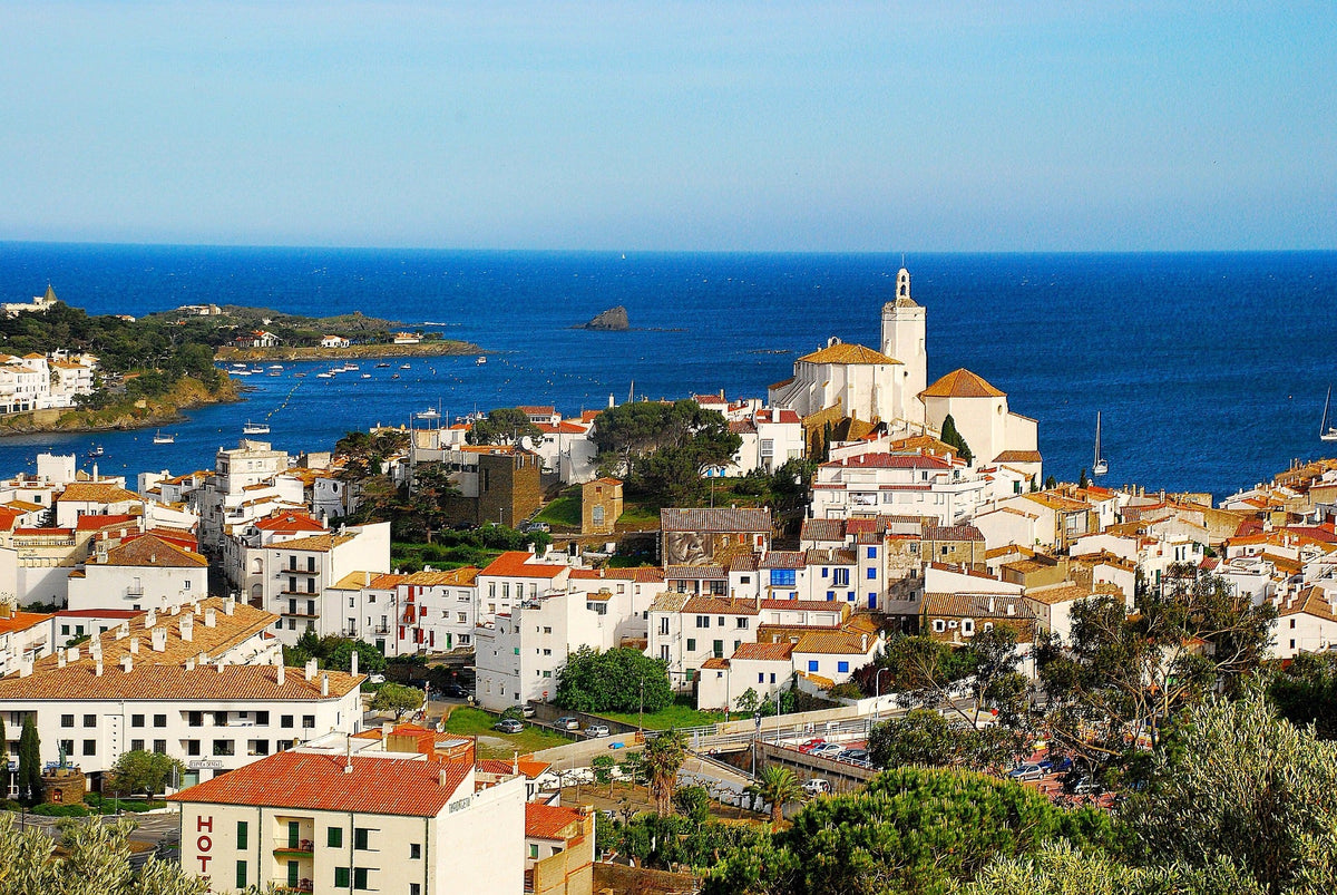 🏖️ Cadaqués, un poble costaner de la Costa Brava amb teulades vermelles i església blanca davant del mar.