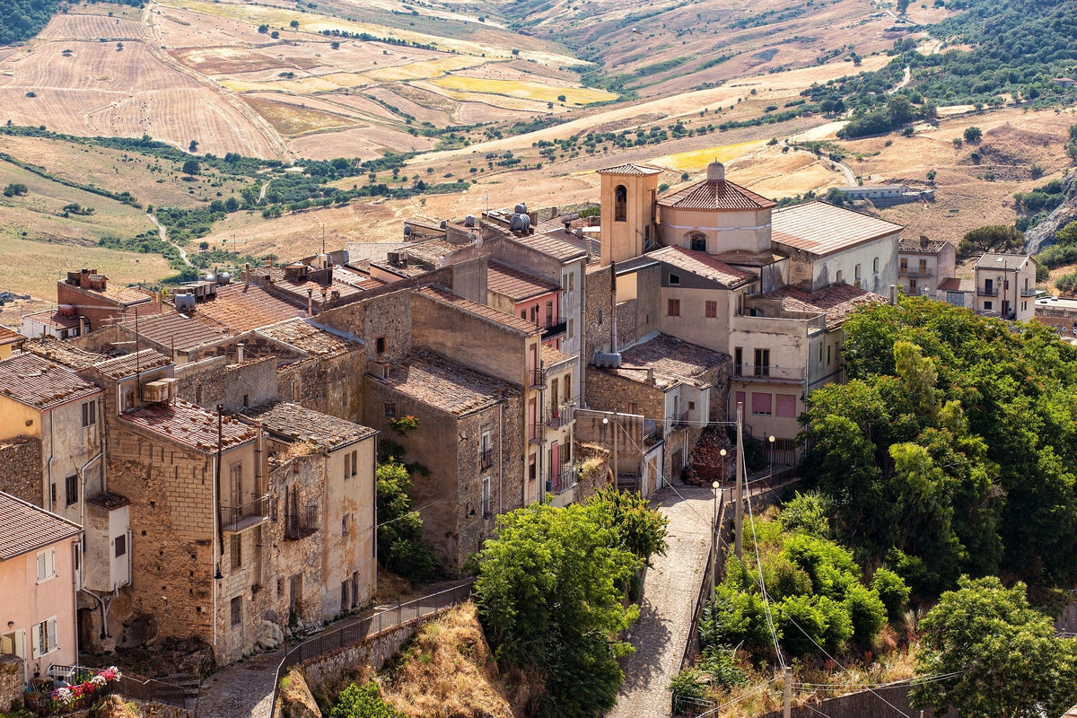 Veduta aerea di un borgo rurale in Sicilia, con edifici storici e paesaggio collinare — ideale per promozione locale e merchandising per aree interne.
