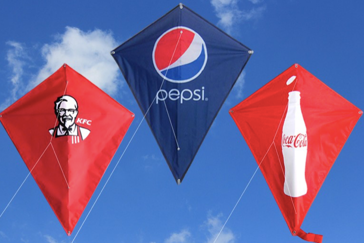 Three full-colour printed diamond kites flying against a blue sky