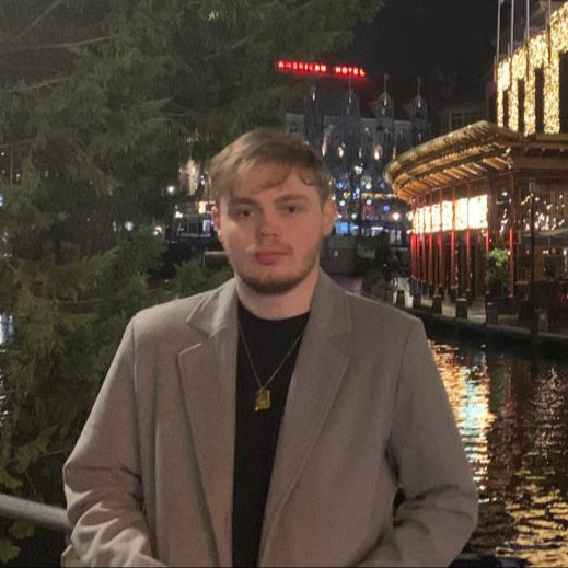 Kyle Cross, Swish & Click’s Commercial & Support team member, standing outdoors at night near a lit-up structure in Amsterdam — focused on supplier partnerships and backend operations across Europe.