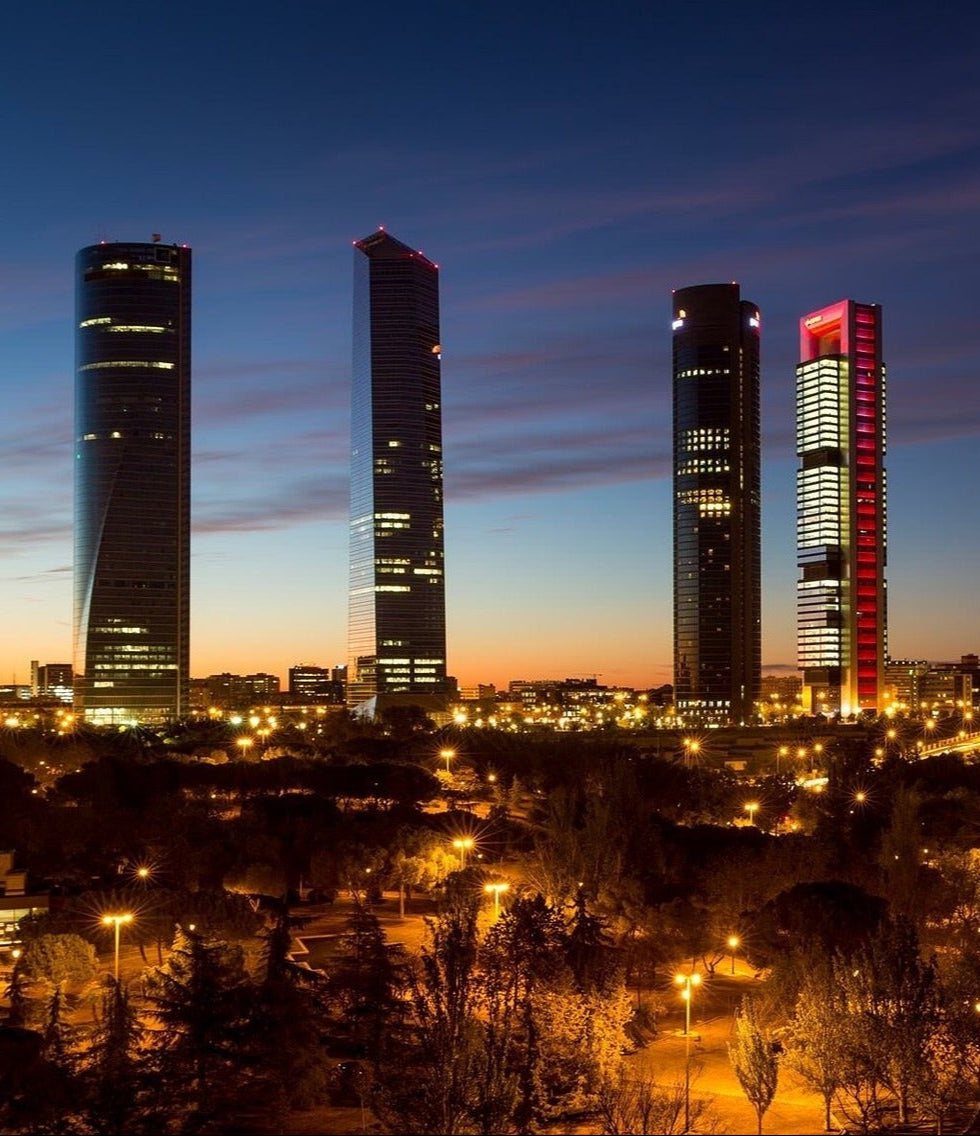 Vista nocturna del distrito financiero Cuatro Torres en Madrid, representando profesionalidad y cobertura nacional para preguntas frecuentes sobre productos promocionales personalizados en España.