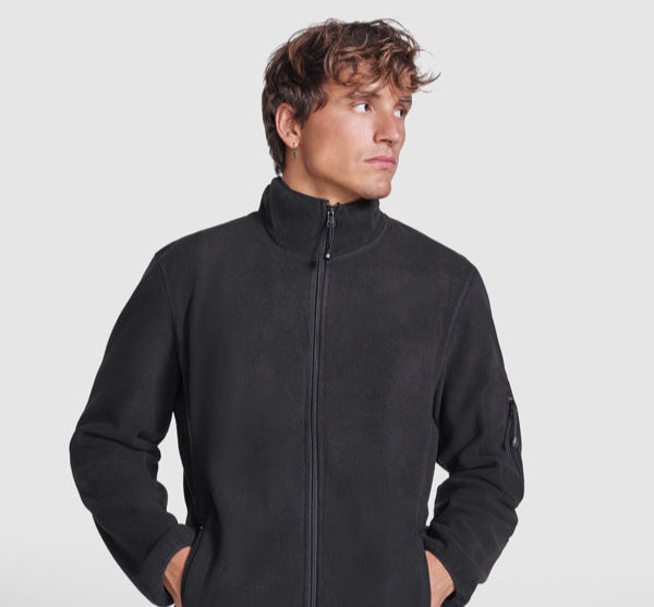 Male model wearing a black promotional fleece jacket — part of ROLY’s branded workwear and custom team clothing range.

Múnla fireann ag caitheamh seaicéad fleece dubh — cuid de raon éadaí oibre branda agus foirne ó ROLY.